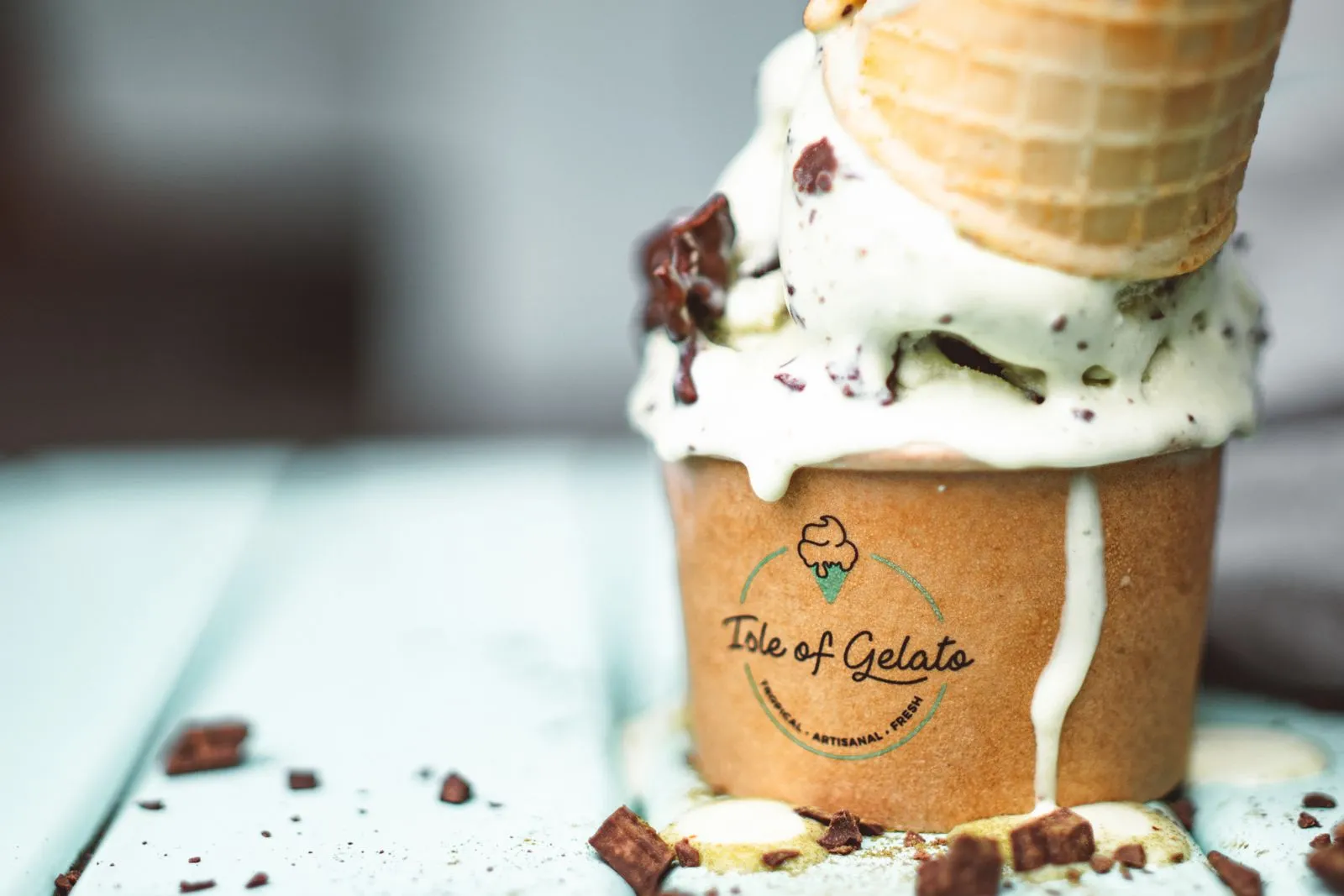 Delicious chocolate chip ice cream cone melting in takeaway cup, showcasing summer's sweet indulgence.